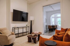 A modern living room with a sofa, coffee table, and a flat-screen TV mounted on the wall. - Designer Loft 3E | Heart of Gold Coast/River North (Chicago)