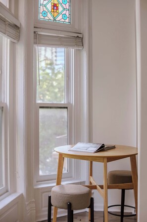A room with a window, a table with a chair, and a book. - Designer Loft 3E | Heart of Gold Coast/River North (Chicago)
