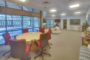 A conference room with a large table, red chairs, and a view through large windows. - Luxury Poconos Townhouse with Resort Perks! (Tannersville)