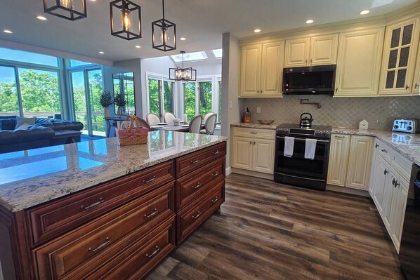 A modern kitchen with a large island, wooden cabinets, and a built-in oven. - Luxury Poconos Townhouse with Resort Perks! (Tannersville)