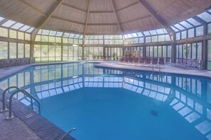 An indoor swimming pool with a wooden roof and large windows. - Luxury Poconos Townhouse with Resort Perks! (Tannersville)