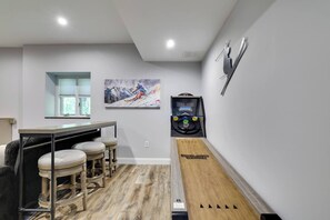 A room with a bar area, a ping pong table, and a wall-mounted game. - Luxury Poconos Townhouse with Resort Perks! (Tannersville)