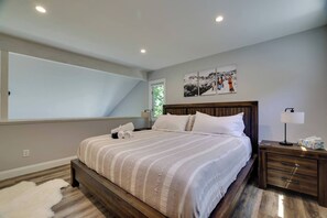 Un dormitorio con una cama grande, una mesita de noche, una lámpara y una ventana.