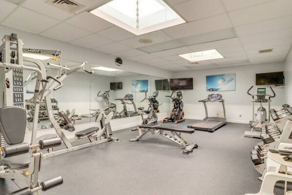 A gym with various exercise equipment, including treadmills, stationary bikes, and weight machines. - Luxury Poconos Townhouse with Resort Perks! (Tannersville)