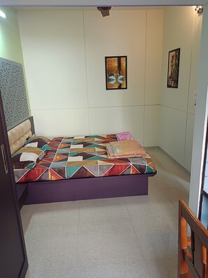 A bedroom with a bed, a wall-mounted artwork, and a patterned wall.