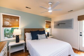 A bedroom with a bed, nightstands, a ceiling fan, and a window with blinds. - Gas Money | Private Pool + Spa | Screened Porch & Sun Decks | 5-Minute Beach Walk | Sleeps 9 (Edisto Beach)
