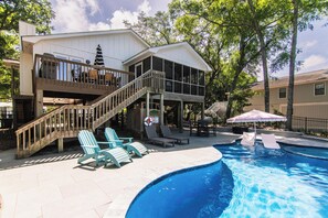 A pool area with a wooden deck, lounge chairs, and a staircase leading to a covered deck. - Gas Money | Private Pool + Spa | Screened Porch & Sun Decks | 5-Minute Beach Walk | Sleeps 9 (Edisto Beach)
