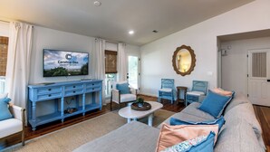 Una sala de estar con televisor, muebles azules, un espejo y una puerta.