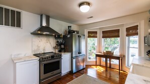 Una cocina moderna con electrodomésticos de acero inoxidable, encimera de mármol y un amplio ventanal con vistas al verdor.
