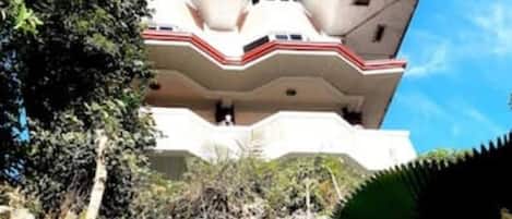 Un edificio de varios pisos con techo plano y un balcón en el nivel superior.