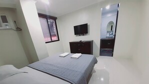 Una camera d'albergo con un letto, una TV, un armadio e uno specchio.