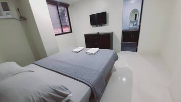 A hotel room with a bed, a TV, a wardrobe, and a mirror.