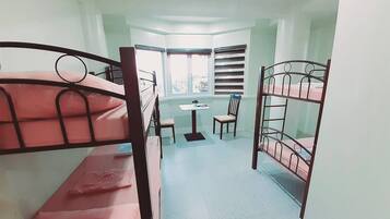 A dormitory room with bunk beds, a small table, and chairs.