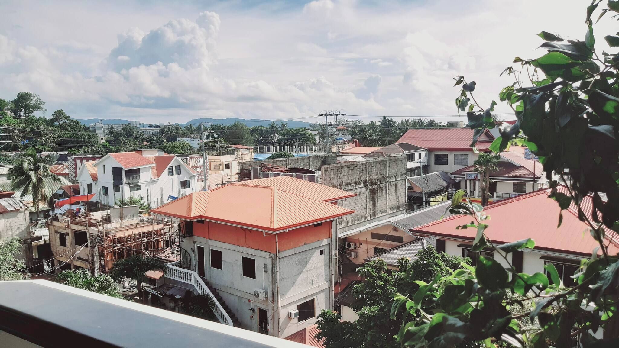 Uma área residencial com vários edifícios, alguns com telhados vermelhos, e um céu limpo.