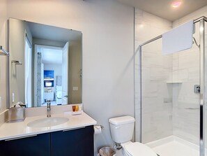 A modern bathroom with a glass-enclosed shower, a white sink, and a toilet. - Luxury 5BR Condo with Rooftop Terrace Near Disney (Kissimmee)