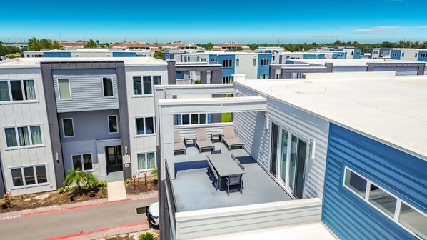 A modern multi-story building with a rooftop patio area. - Luxury 5BR Condo with Rooftop Terrace Near Disney (Kissimmee)