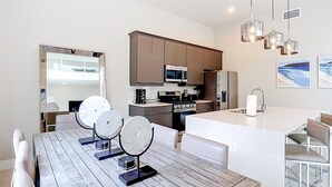 Uma cozinha moderna com ilha central, eletrodomésticos embutidos e iluminação pendente.