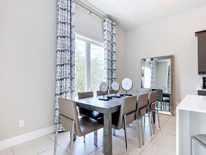 A dining area with a wooden table, six chairs, and three round mirrors on stands. - Luxury 5BR Condo with Rooftop Terrace Near Disney (Kissimmee)