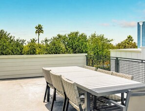 Eine Terrasses mit Tisch und Stühlen, umgeben von einer niedrigen Mauer und Pflanzen.