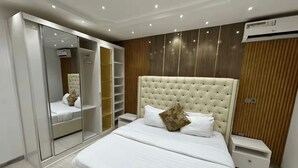 Ein Schlafzimmer mit einem großen Bett, einem Schrank mit Spiegel und einer Decken-Klimaanlage.