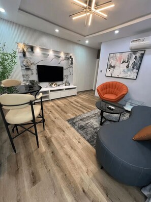 A modern living room with a flat-screen TV, a sofa, a chair, and a coffee table. - Radiant 1-Bedroom Apartment in Lekki 1 with Fast Wi-Fi & 24/7 Power (Lagos)