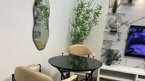 Ein Essbereich mit einem runden Tisch, vier Stühlen, einem Spiegel an der Wand und einem Fernseher auf einem Regal.