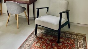 Ett rum med ett skrivbord, en stol, en stor spegel och en mönstrad matta.