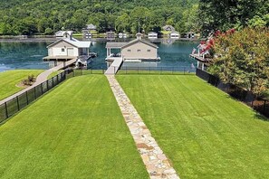 A lakeside property with a well-maintained lawn, dock, and several buildings. - Waters Edge- Lakefront Luxury on Lake Guntersville (Grant)