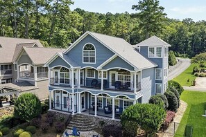 A large, two-story house with multiple balconies and a covered front porch. - Waters Edge- Lakefront Luxury on Lake Guntersville (Grant)