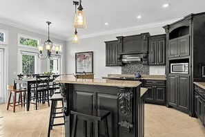 A kitchen with dark cabinetry, a central island, and pendant lighting. - Waters Edge- Lakefront Luxury on Lake Guntersville (Grant)