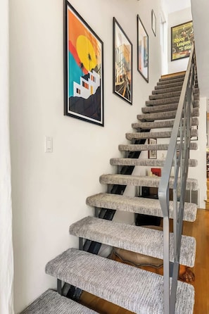 Eine Treppe mit einem taktil anmutenden Teppichlaufgeländer und Stufen, die zu einer oberen Etage führen.