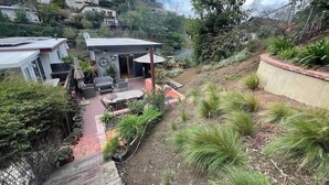 Propiedad residencial con patio, mobiliario exterior y jardín con diversas plantas.