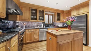 Una cocina moderna con armarios de madera, un refrigerador de acero inoxidable y una isla central con tabla de cortar.