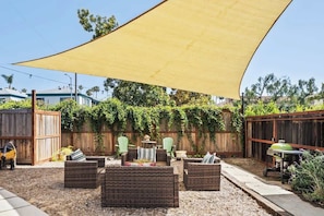 An outdoor patio area with wicker furniture, a table, and a grill. - The Black Fig | Hollywood Character Modern Comfort (Los Angeles)