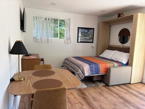 A bedroom with a bed, a desk, a chair, a lamp, and a window with curtains. - Fabulous modern bungalow with deck and private fenced yard. Dog friendly. (Crescent City)