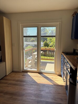 Ein Zimmer mit einer Schiebetür zu einer Terrasse im Freien, mit Holzdeck und Metallgeländer.