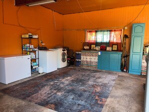Ein Waschraum mit Waschmaschine, Trockner und Regalen voller Reinigungsmittel.