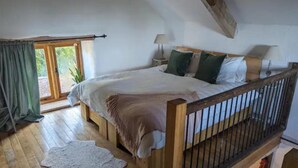 A bedroom with a wooden bed, a nightstand, a lamp, and a view of the outdoors through a sliding door.