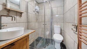 Ein Badezimmer mit Duschkabine aus Glas, einem weißen Waschbecken und einer Toilette.