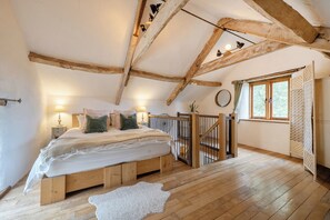 A bedroom with a wooden ceiling, a bed with pillows, a nightstand, a window with curtains, and a wooden floor. - 1 Bed Barn - Sleeps 2 - Pool - Garden - Bbq (Taunton)