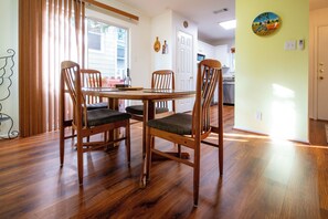 A dining area with a wooden table and chairs, a kitchen in the background, and a door leading to another room. - Extended Stay in Townhome : Gated Community at Medical Center District (San Antonio)