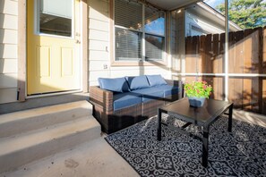 A covered patio area with a sofa, a table, and a potted plant. - Extended Stay in Townhome : Gated Community at Medical Center District (San Antonio)