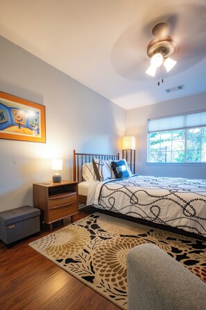 A bedroom with a bed, bedside table, lamp, and a painting on the wall. - Extended Stay in Townhome : Gated Community at Medical Center District (San Antonio)