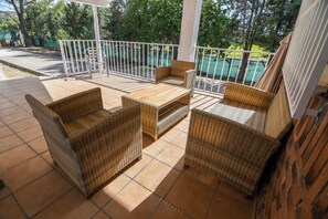 A covered outdoor seating area with wicker furniture and a tiled floor. - Casa Dolly - Elegant Villa directly on the Tajo (VIILLAMANRIQUE DE TAJO)