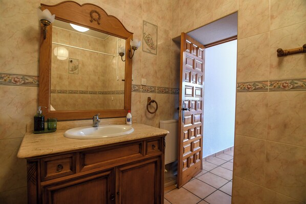 A bathroom with a wooden vanity, a mirror, a sink, and a towel rack.