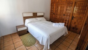 Una camera da letto con un letto, un comodino, un tappeto di iuta e un armadio in legno.