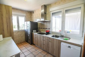 A compact kitchen with a dishwasher, a refrigerator, and a sink. - Casa Dolly - Elegant Villa directly on the Tajo (VIILLAMANRIQUE DE TAJO)