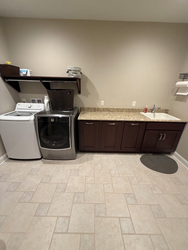 A laundry area with a washing machine, dryer, and stacked laundry baskets. - Tranquil luxurious 4-bedroom home on a scenic 2.5 ace lot, min. from Penn State. (Port Matilda)