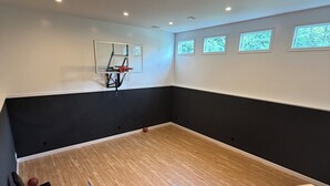 Ein Zimmer mit Basketballkorb, einem Stuhl und einer Treppe.