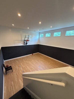 A room with a basketball hoop, a chair, and a staircase. - Tranquil luxurious 4-bedroom home on a scenic 2.5 ace lot, min. from Penn State. (Port Matilda)